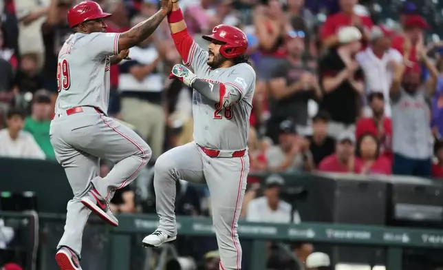 Cincinnati Reds third base coach Willie Harris, left, celebrates with Eugenio Su·rez as he circles the bases after hitting a solo home run off Colorado Rockies relief pitcher Jimmy Herget in the sixth inning of a baseball game Friday, July 17, 2026, in Denver. (AP Photo/David Zalubowski)