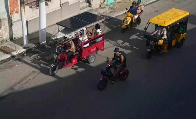 People ride in electric tricycles in Havana, Cuba, Friday, July 10, 2026. (AP Photo/Ramon Espinosa)