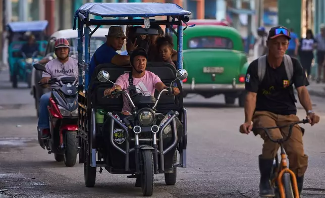 People ride in an electric tricycle in Havana, Cuba, Friday, July 10, 2026. (AP Photo/Ramon Espinosa)