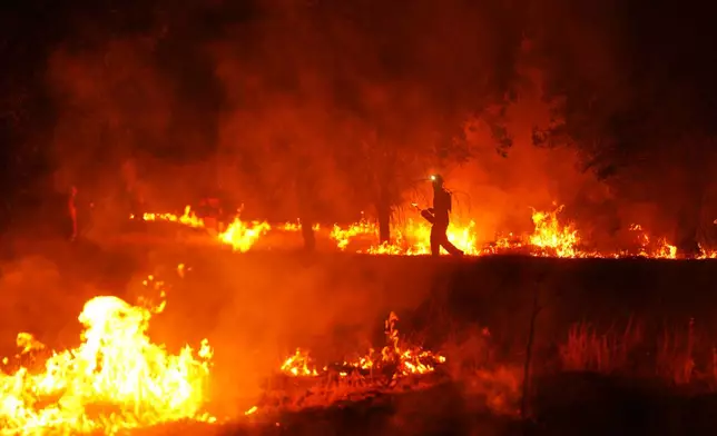Firefighters use controlled burning to halt a wildfire that continues to spread near Cebreros, Ávila province, Spain, Tuesday, July 28, 2026. (AP Photo/Manu Fernandez)