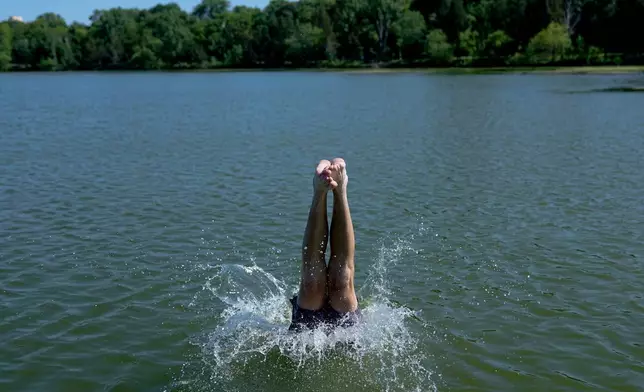 A swimmer dives into Cedar Lake during an extreme heat warning Monday, July 13, 2026, in Minneapolis. (AP Photo/Ellen Schmidt)