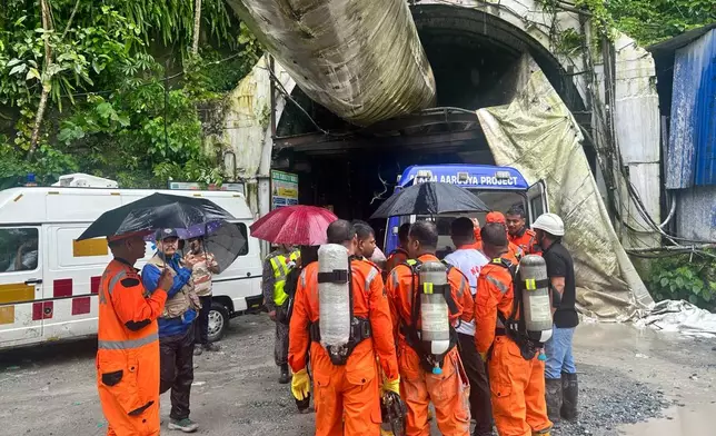 Members of the rescue team carry oxygen cylinders outside the entrance to an under-construction tunnel at a hydropower project in Samardung village, about 40 kilometers (25 miles) from Gangtok, India, Tuesday, July 21, 2026. (AP Photo)