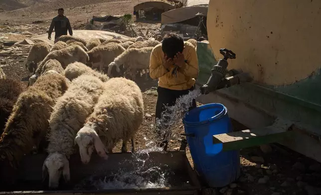 Hamoudi, 10, washes his face as he gives water to his family's sheep at a Palestinian community in the northern Jordan Valley in the occupied West Bank, Tuesday, June 23, 2026. (AP Photo/Leo Correa)
