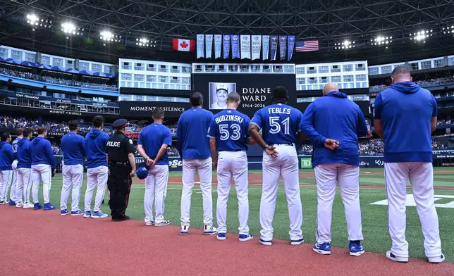 Players and coaches of the Toronto Blue Jays recognize a moment of silence on the announcement of the passing of former Blue Jays pitcher Duane Ward prior to the start of the game against the Chicago White Sox in MLB baseball action in Toronto on Sunday, July 19, 2026. (Jon Blacker/The Canadian Press via AP)