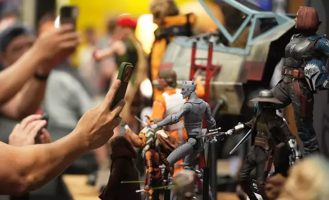 Comic-Con attendees take pictures of model figures at the Sideshow Collectibles booth during preview night at Comic-Con International on Wednesday, July 22, 2026, in San Diego. (AP Photo/Chris Pizzello)