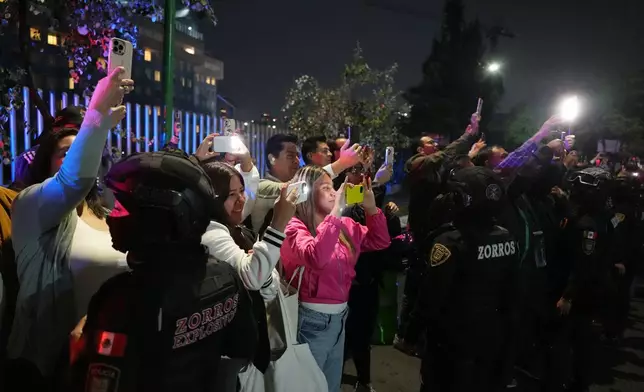 Fans take photos as the England team bus arrives at the hotel where they will stay in Mexico City ahead of its World Cup round of 16 soccer match against Mexico, Friday, July 3, 2026. (AP Photo/Eduardo Verdugo)