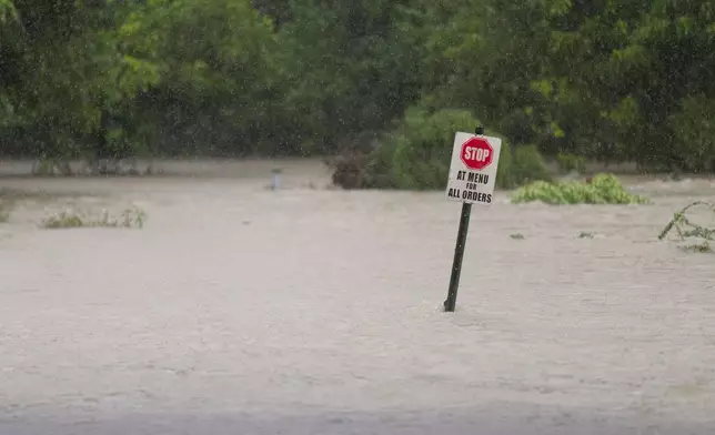 Flood water flows through a restaurant's parking lot on Wednesday, July 15, 2026, in Boerne, Texas. (AP Photo/Darren Abate)