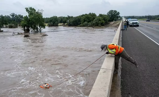 A U.S. Geological Survey hydrologic technician surveys water levels along the Pedernales River using an acoustic doppler profiler on Thursday, July 16, 2026, in Fredericksburg, Texas. (AP Photo/Joel Angel Juarez)
