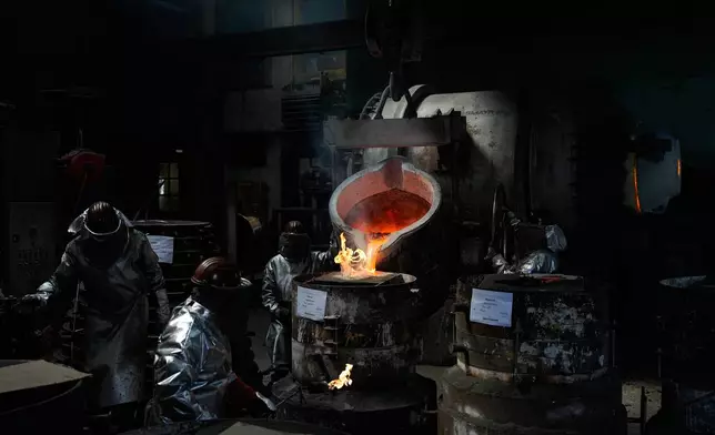 Employees cast bronze bells at the 400-year-old, family-owned Grassmayr bell foundry in Innsbruck, Austria, Friday, July 17, 2026. (AP Photo/Matthias Schrader)