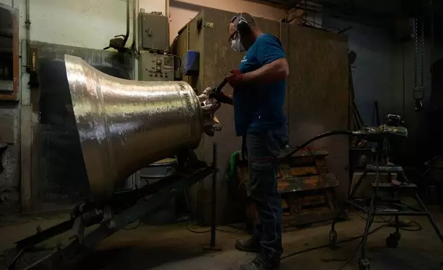 Anto Bastianovic polishes a bronze bell at the 400-year-old, family-owned Grassmayr bell foundry in Innsbruck, Austria, Friday, July 17, 2026. (AP Photo/Matthias Schrader)