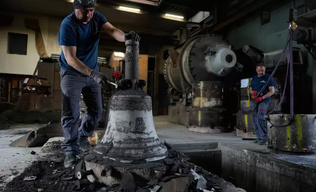 Jotka Omar unpacks a bronze bell as he works at the 400-year-old, family-owned Grassmayr bell foundry in Innsbruck, Austria, Friday, July 17, 2026. (AP Photo/Matthias Schrader)