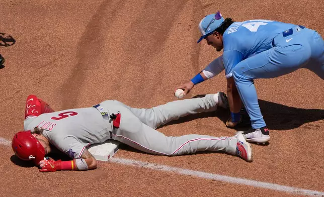 Philadelphia Phillies' Bryson Stott (5) beats the tag at third by Kansas City Royals third baseman Josh Rojas after hitting a triple during the fifth inning of a baseball game Sunday, July 5, 2026, in Kansas City, Mo. (AP Photo/Charlie Riedel)