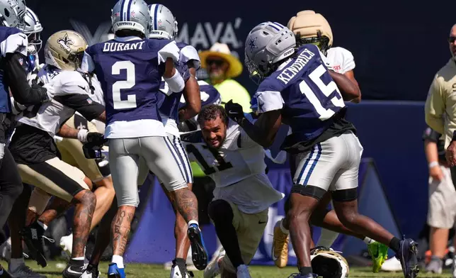 New Orleans Saints wide receiver Ronnie Bell, center, fights with members of the Dallas Cowboys, including safety Cobie Durant (2) and cornerback Derion Kendrick (15) during an NFL football joint practice, Tuesday, Aug. 18, 2026, in Oxnard, Calif. (AP Photo/Mark J. Terrill)