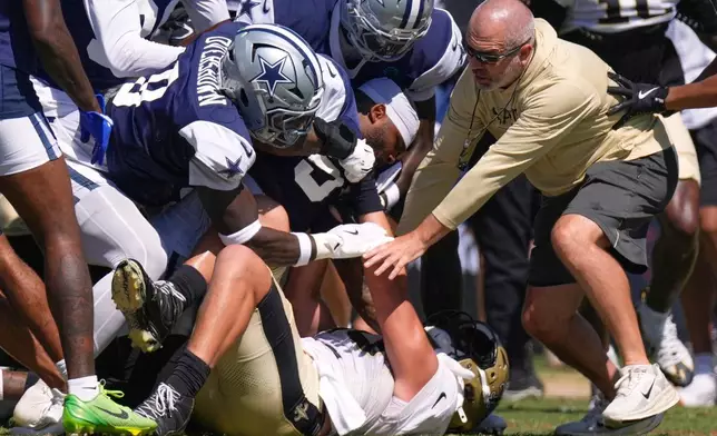 Dallas Cowboys linebacker Demarvion Overshown, left, and outside linebacker Sam Williams, center, fight, with New Orleans Saints tight end Moliki Matavao, below, during an NFL football joint practice, Tuesday, Aug. 18, 2026, in Oxnard, Calif. (AP Photo/Mark J. Terrill)