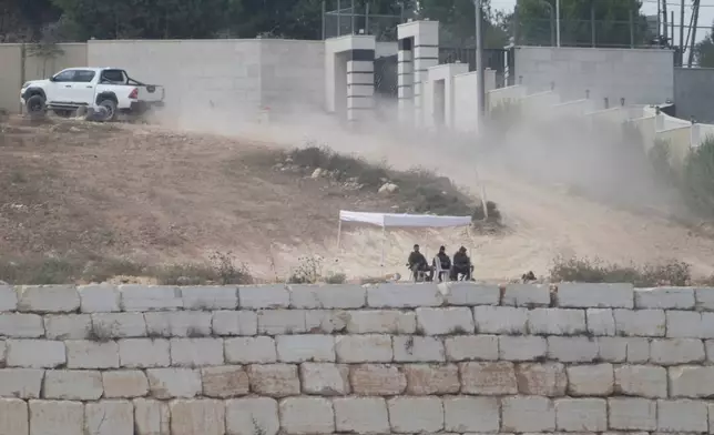 Israeli soldiers sit under a tent in front of the house of Ohio-based Palestinian-American landlord Loui Ridi, that is besieged by Israeli settlers for over a week, in the occupied West Bank village of Qusra, south of Nablus, Tuesday, Aug. 18, 2026. (AP Photo/Majdi Mohammed)