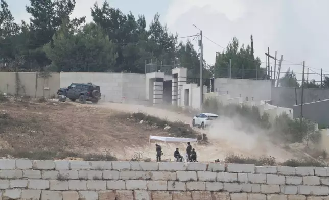 Israeli soldiers sit under a tent in front of the house of Ohio-based Palestinian-American landlord Loui Ridi, that is besieged by Israeli settlers for over a week, in the occupied West Bank village of Qusra, south of Nablus, Tuesday, Aug. 18, 2026. (AP Photo/Majdi Mohammed)