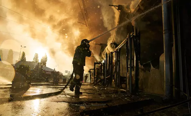 Firefighters try to put out a fire at a city book market following a Russian missile attack in Kyiv, Ukraine, early Sunday, Aug. 16, 2026. (AP Photo/Francisco Seco)