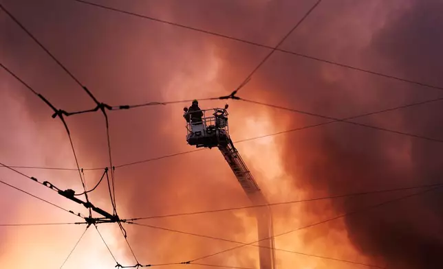 Firefighters try to put out a fire at a city book market following a Russian missile attack in Kyiv, Ukraine early Sunday, Aug. 16, 2026. (AP Photo/Francisco Seco)