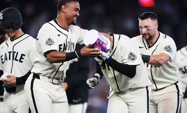 Seattle Mariners' Julio Rodríguez, left, puts a gum bucket on the head of teammate Colt Emerson as they celebrate Emerson's walk-off RBI single during the ninth inning for a win over the Minnesota Twins in a baseball game, Sunday, Aug. 2, 2026, in Seattle. (AP Photo/Lindsey Wasson)