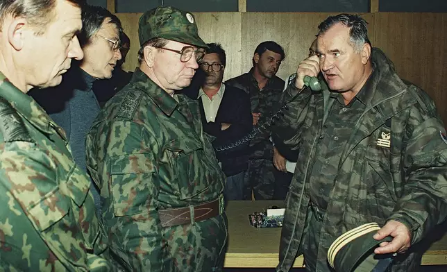 FILE - Bosnian Serb General Ratko Mladic, right, talks on the phone next to Russian Army General Vladimir Zurbenko, center, during the visit of a Russian Army delegation to the Bosnian town of Banja Luka in Oct. 1995. (AP Photo/Radivoje Pavicic, File)
