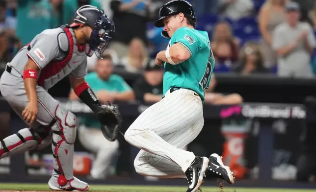 Miami Marlins' Griffin Conine, right, scores past Washington Nationals catcher Keibert Ruiz, left, on a sacrifice fly hit by Otto Lopez during the sixth inning of a baseball game, Sunday, Aug. 23, 2026, in Miami. (AP Photo/Lynne Sladky)