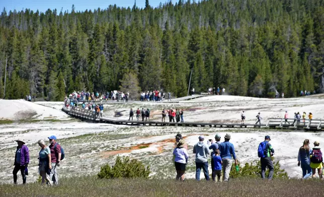 FILE - Tourists walk along a boardwalk in Upper Geyser Basin on June 22, 2022, in Yellowstone National Park, Wyo. (AP Photo/Matthew Brown, File)