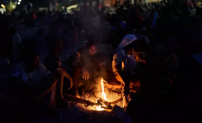 Migrants who crossed into Spain from Morocco gather around a bonfire on a beach in the Spanish enclave of Ceuta, Sunday, Aug. 2, 2026. (AP Photo/Bernat Armangue)