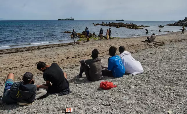 Migrants who crossed into Spain from Morocco gather on a beach in the Spanish enclave of Ceuta, Monday, Aug. 3, 2026. (AP Photo/Antonio Sempere)
