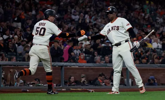 San Francisco Giants' Christian Koss (50) is congratulated by Rafael Devers, right, after scoring on a sacrifice fly hit by Drew Gilbert during the fifth inning of a baseball game against the Arizona Diamondbacks in San Francisco, Thursday, Aug. 27, 2026. (AP Photo/Jed Jacobsohn)
