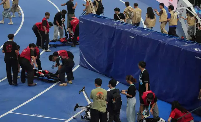 Humanoid robots are carried off the track after competing in the 100m race during the World Humanoid Robot Games in Beijing, Tuesday, Aug. 25, 2026. (AP Photo/Achmad Ibrahim)
