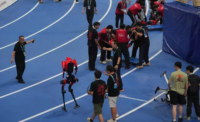 Humanoid robots are carried off the track after competing in the 100m race during the World Humanoid Robot Games in Beijing, Tuesday, Aug. 25, 2026. (AP Photo/Achmad Ibrahim)