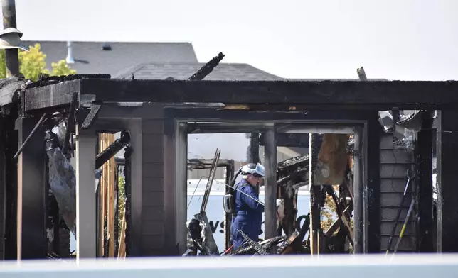 An investigator is seen inside the burned remains of a house where eight family members died in a weekend shooting and fire, Wednesday, Aug. 26, 2026, near Billings, Mont. (AP Photo/Matthew Brown)