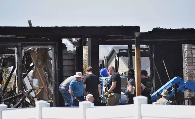 Investigators work at the scene Tuesday, Aug. 25, 2026, where a family was killed and the house burned in Billings, Mont. (AP Photo/Matthew Brown)