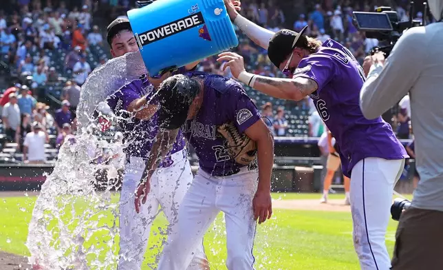 Colorado Rockies starting pitcher Kyle Freeland, center, is doused by second baseman Edouard Julien, left, and center fielder Cole Carrigg after Freeland tossed a complete game in the Rockies' victory over the Kansas City Royals in a baseball game Sunday, Aug. 2, 2026, in Denver. (AP Photo/David Zalubowski)