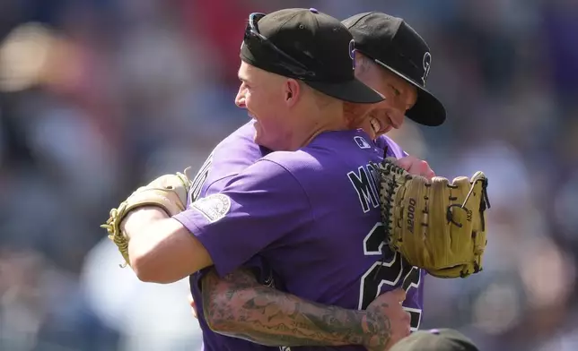 Colorado Rockies left fielder Mickey Moniak, front, hugs starting pitcher Kyle Freeland, back, after his complete baseball game victory over the Kansas City Royals, Sunday, Aug. 2, 2026, in Denver. (AP Photo/David Zalubowski)