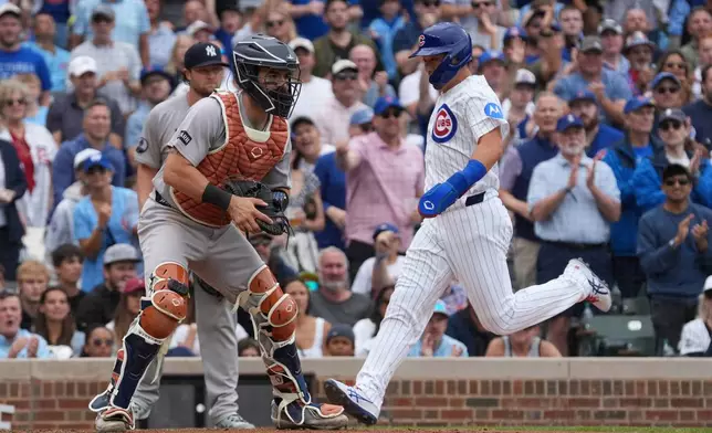Chicago Cubs' Seiya Suzuki, right, scores as New York Yankees catcher Austin Wells, left, waits for a throw during the fourth inning of a baseball game Sunday, Aug. 2, 2026, in Chicago. (AP Photo/David Banks)