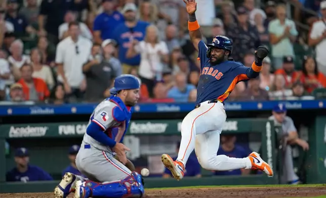 Houston Astros' Taylor Trammell, right, scores as Texas Rangers catcher Austin Wynns handles the throw during the seventh inning of a baseball game Sunday, Aug. 2, 2026, in Houston. (AP Photo/David J. Phillip)