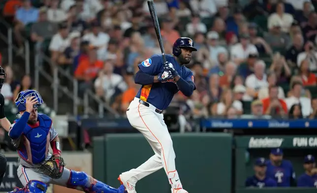 Houston Astros' Yordan Alvarez, right, hits a two-run double as Texas Rangers catcher Austin Wynns watches during the seventh inning of a baseball game Sunday, Aug. 2, 2026, in Houston. (AP Photo/David J. Phillip)