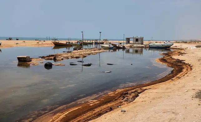 Oil residue lines the shore near fishing boats on Qeshm Island, Iran, Thursday, Aug. 13, 2026, amid ongoing wartime attacks on vessels and infrastructure in and around the Strait of Hormuz, though the spill's source has not been independently determined.(Amirhosein Khorgooi/ISNA via AP)