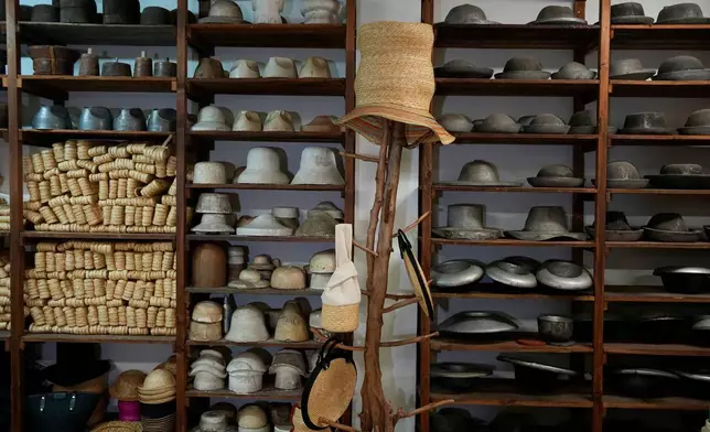 Hats are displayed alongside materials using in their production on hangers and shelves at a shop in Athens, Greece, Tuesday, Aug. 11, 2026. (AP Photo/Thanassis Stavrakis)