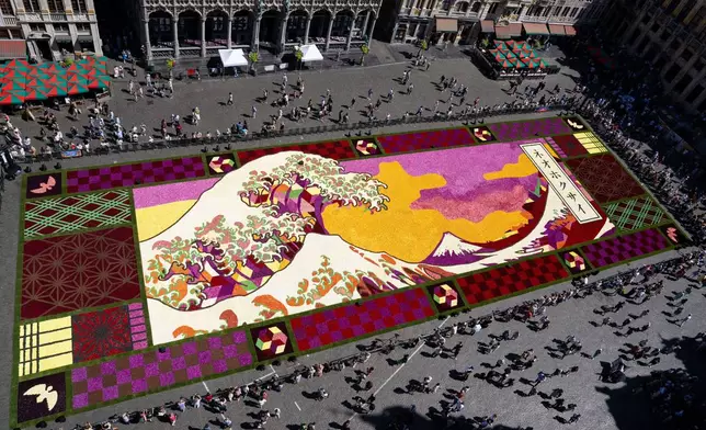 An overview of a giant flower carpet inspired by The Great Wave off Kanagawa by Japanese artist Katsushika Hokusai at the historic Grand Place in Brussels, Thursday, Aug. 13, 2026. (AP Photo/Marius Burgelman)