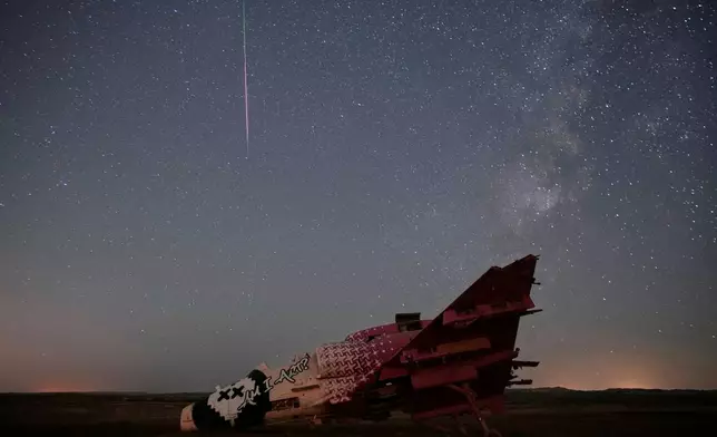 A meteor streaks above a destroyed aircraft used for training purposes in the Negev Desert, Israel, Thursday, Aug. 13, 2026. (AP Photo/Ohad Zwigenberg)