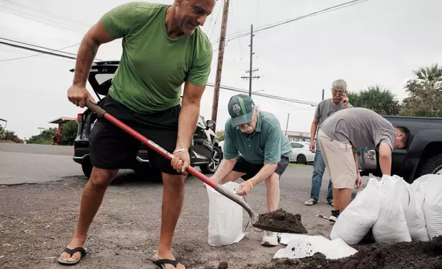 Shaheer Faltas, left, and his father-in-law, Joe Brosnan, fill sandbags in preparation for the arrival of Tropical Storm Lala in Captain Cook, Hawaii, Friday, Aug. 14, 2026. (Stephen Lam/San Francisco Chronicle via AP)