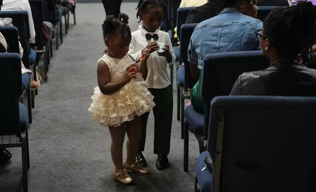 Children walk the aisles of the Word of Life Center church carrying snacks during a service in Salisbury, Md. Sunday, Aug. 2, 2026. (AP Photo/Luis Andres Henao)