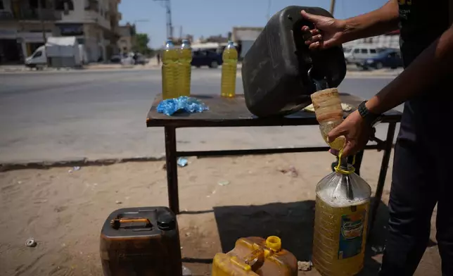 A Palestinian vendor fills bottles with diesel as he offers them for sale in al-Maghazi refugee camp, central Gaza Strip, Saturday, Aug. 15, 2026. (AP Photo/Abdel Kareem Hana)