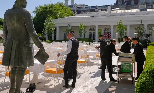 FILE - A statue of Ben Franklin is seen as servers prepare the Rose Garden for a dinner after President Donald Trump hosted the 2026 College Football Playoff national champions Indiana University on the South Lawn of the White House, May 11, 2026, in Washington. (AP Photo/Jacquelyn Martin, File)