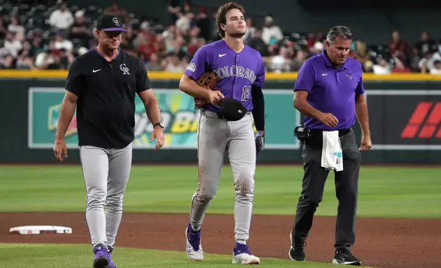 Colorado Rockies' Kyle Karros (12) leaves the game after colliding with Ezequiel Tovar on a ball hit by Arizona Diamondbacks' Ketel Marte in the sixth inning of a baseball game, Tuesday, Aug 11, 2026, in Phoenix. (AP Photo/Rick Scuteri)