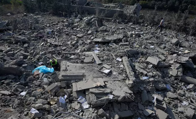 A rescue worker, left, searches for victims under the rubble of a home that was hit by an Israeli airstrike in Ansar village, southern Lebanon, Saturday, Aug. 15, 2026. (AP Photo/Mohammed Zaatari)