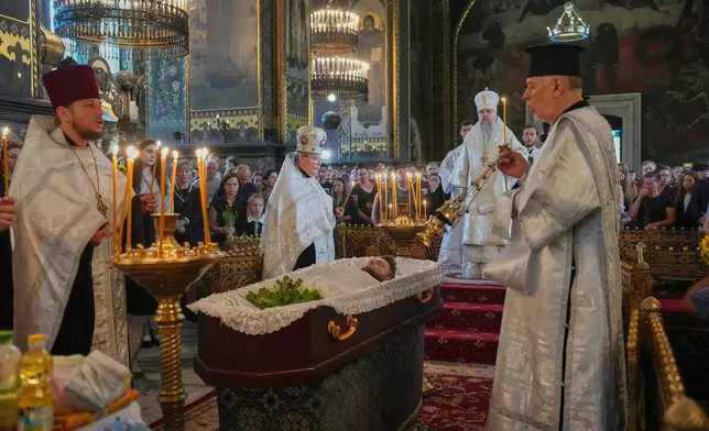 Priests preside over a farewell ceremony for Oleksiy Yukov, who was fatally wounded while exhuming bodies of killed soldiers in the frontline in Donetsk region, in St. Volodymyr Cathedral in Kyiv, Ukraine, Saturday, Aug. 8, 2026. (AP Photo/Efrem Lukatsky)