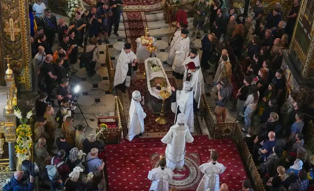 Priests preside over a farewell ceremony for Oleksiy Yukov, who was fatally wounded while exhuming bodies of killed soldiers in the frontline in Donetsk region, in St. Volodymyr Cathedral in Kyiv, Ukraine, Saturday, Aug. 8, 2026. (AP Photo/Efrem Lukatsky)